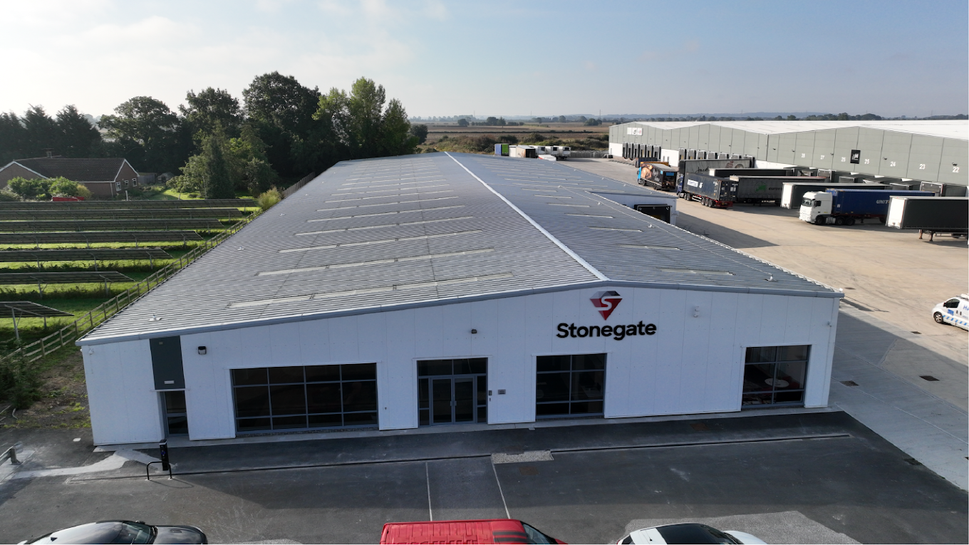 Aerial view of a white Stonegate warehouse with loading docks beside fields and an industrial lot.