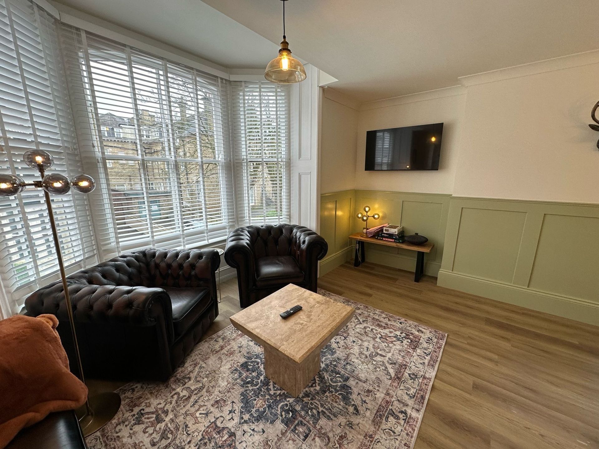 Cozy living room with black leather chairs, patterned rug, wood coffee table, and wall-mounted TV.