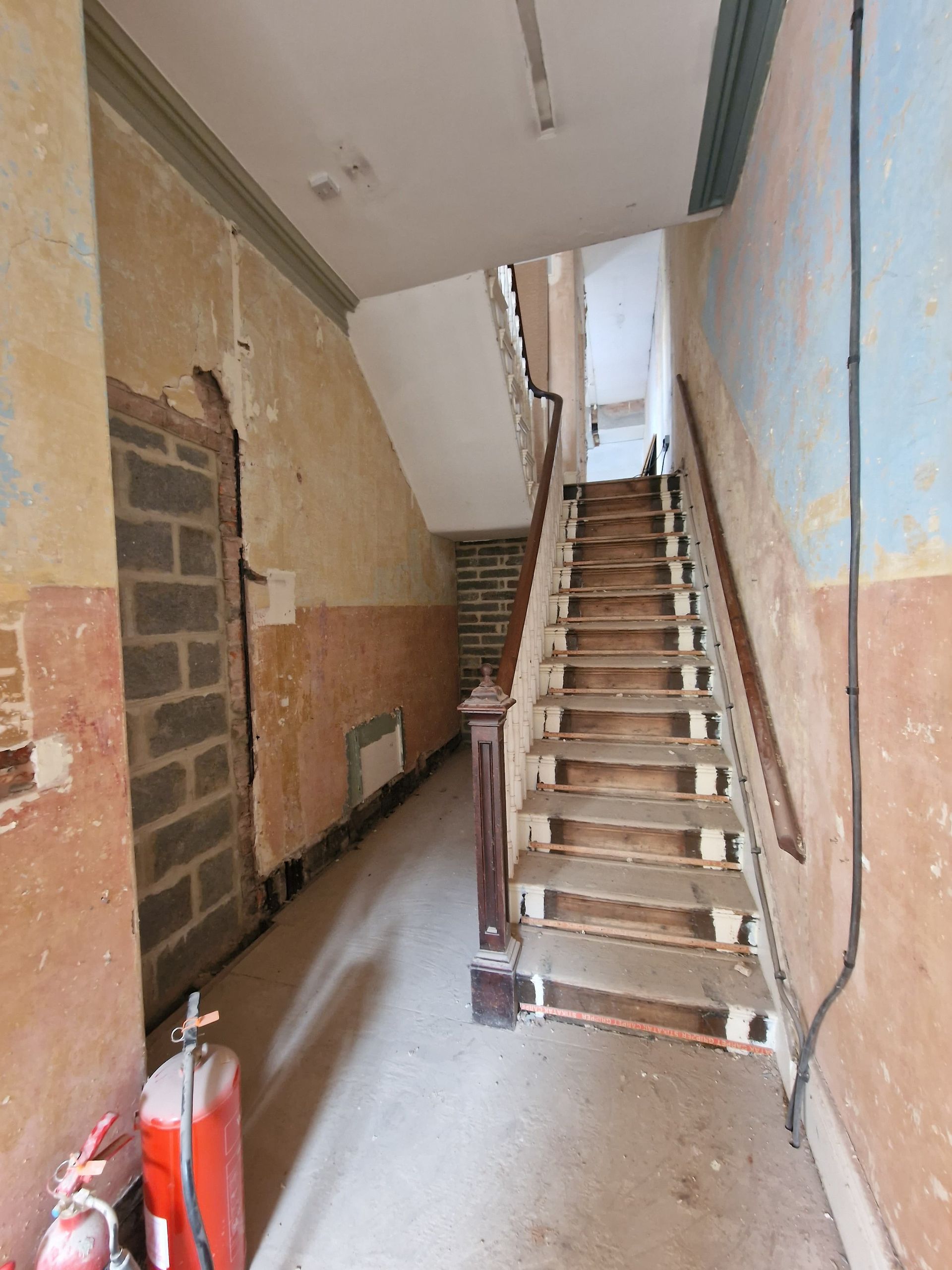 Indoor stairway under construction with unfinished concrete steps and walls in a narrow corridor