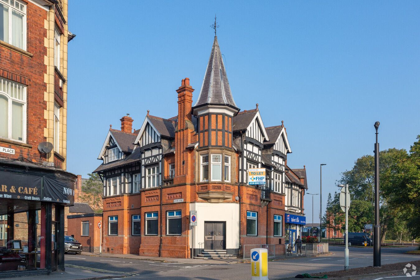 Victorian red-brick corner building with a turret on a sunny street intersection