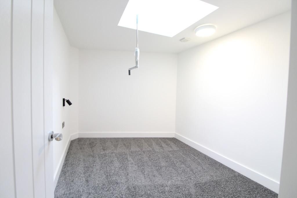 Empty white room with gray carpet and a skylight window, viewed from the doorway