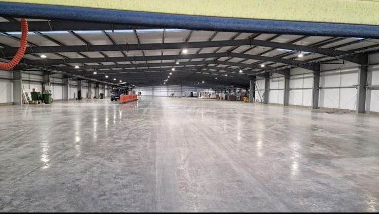 Empty industrial warehouse interior with polished concrete floor and metal beams