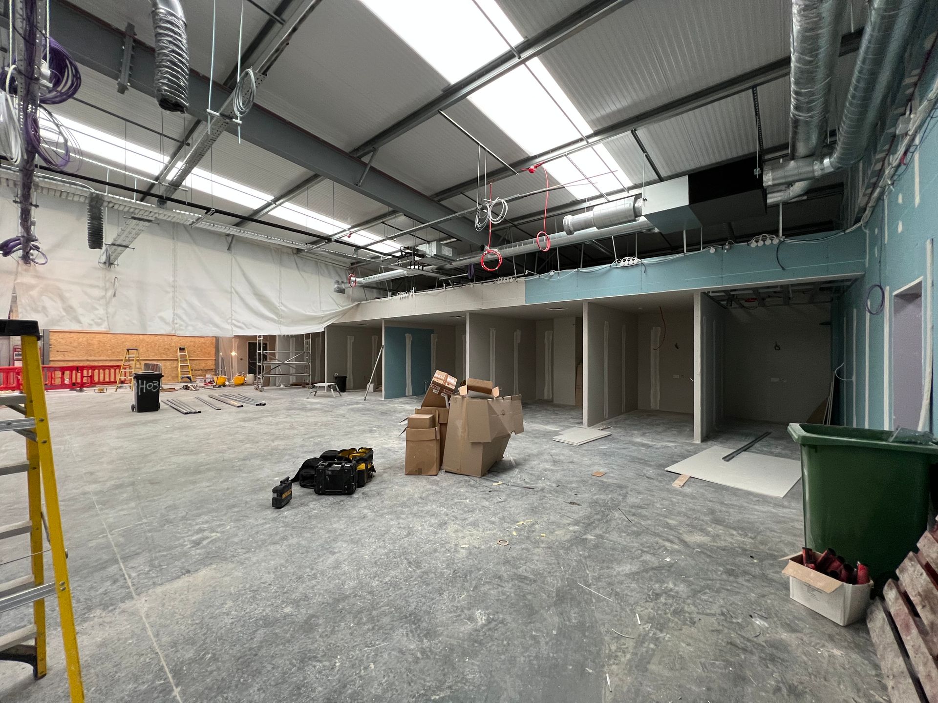 Interior of a construction site with exposed ceiling, debris, boxes, and unfinished walls and columns