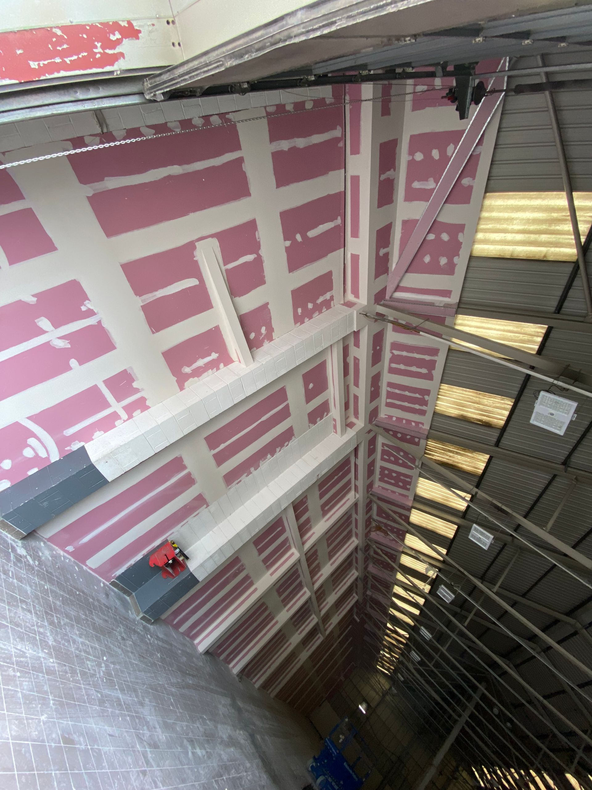 Insulated attic ceiling with pink foam board and exposed metal framing, viewed from below