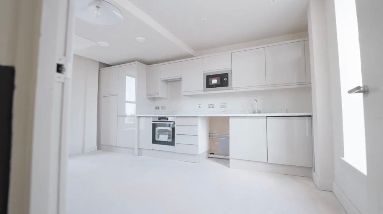 Bright modern white kitchen with cabinets, stove, and built-in microwave.
