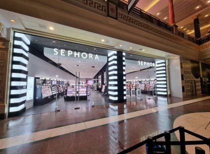 Sephora storefront in a shopping mall, with bright black-and-white striped entrances and illuminated signs