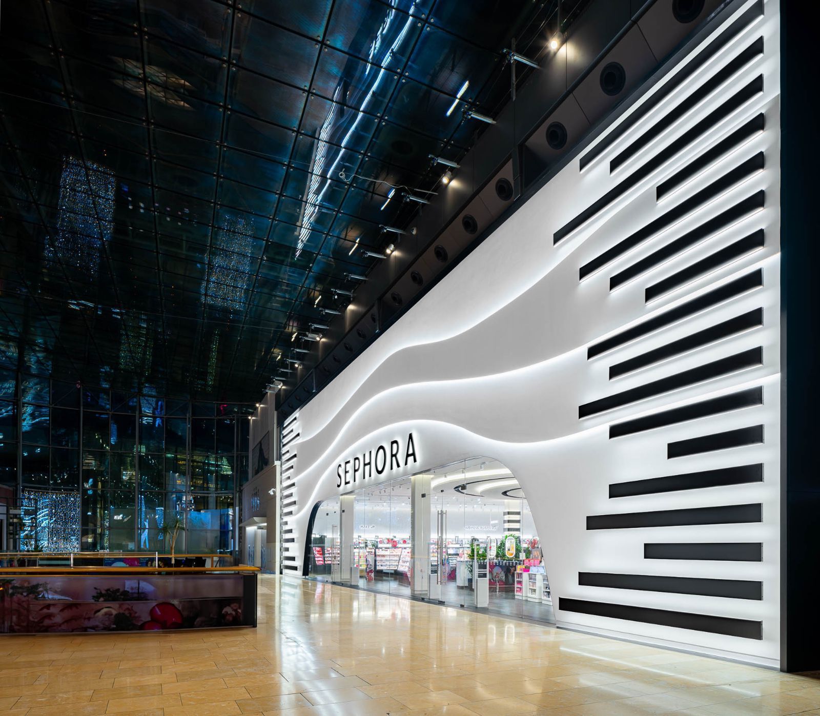 SEPHORA store entrance with white wave-shaped facade and black slats in a sleek indoor mall.