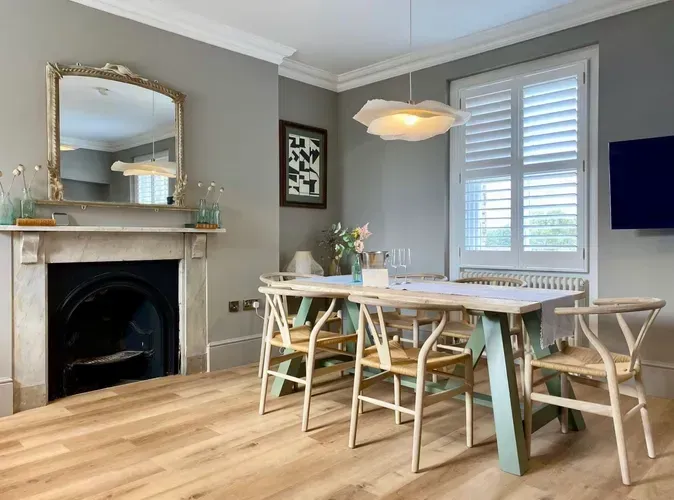 Bright dining room with a table, chairs, fireplace, and gray walls near a window and TV
