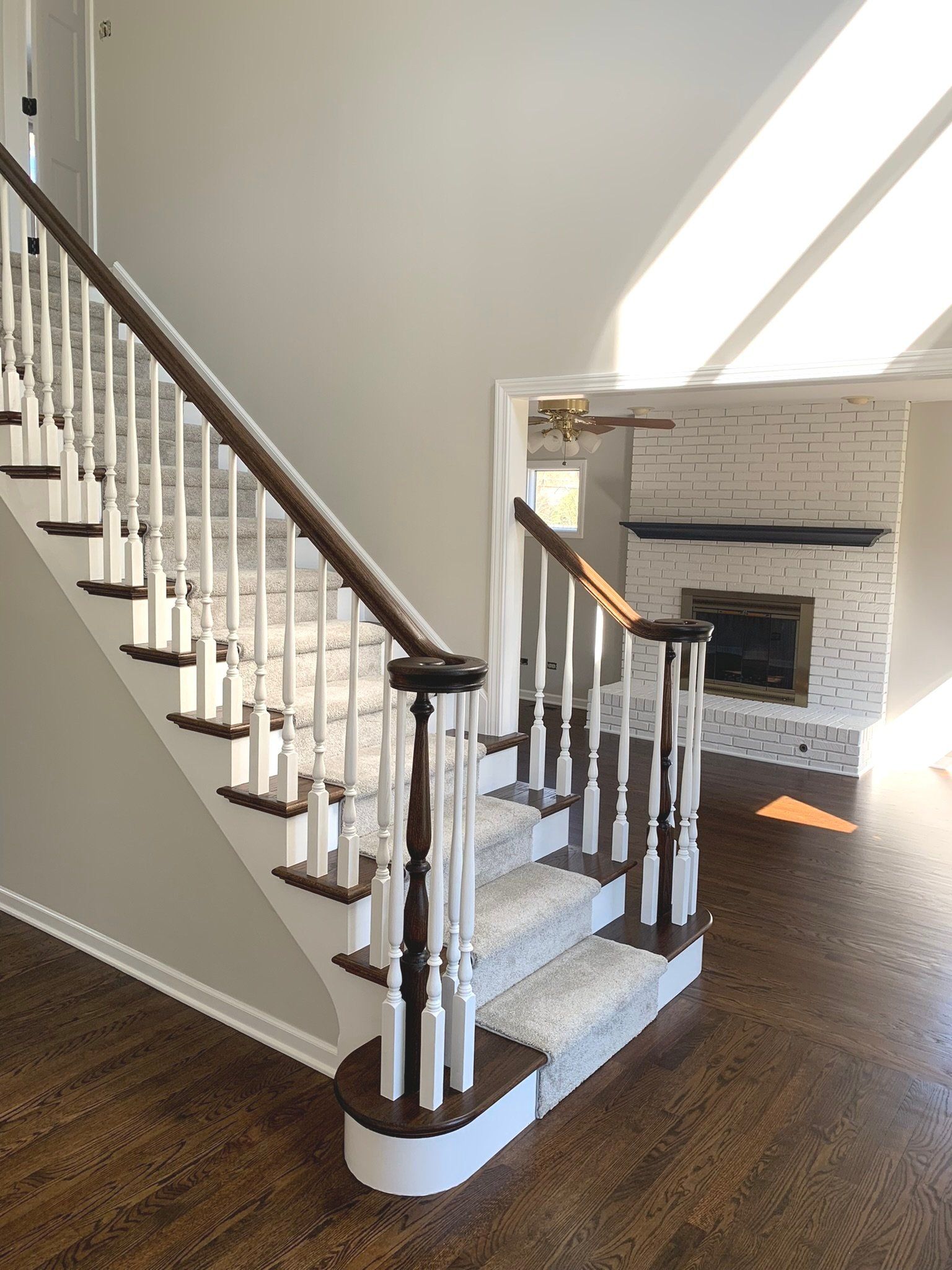 Staircase with wood steps and white spindles, leading to a room with a fireplace.