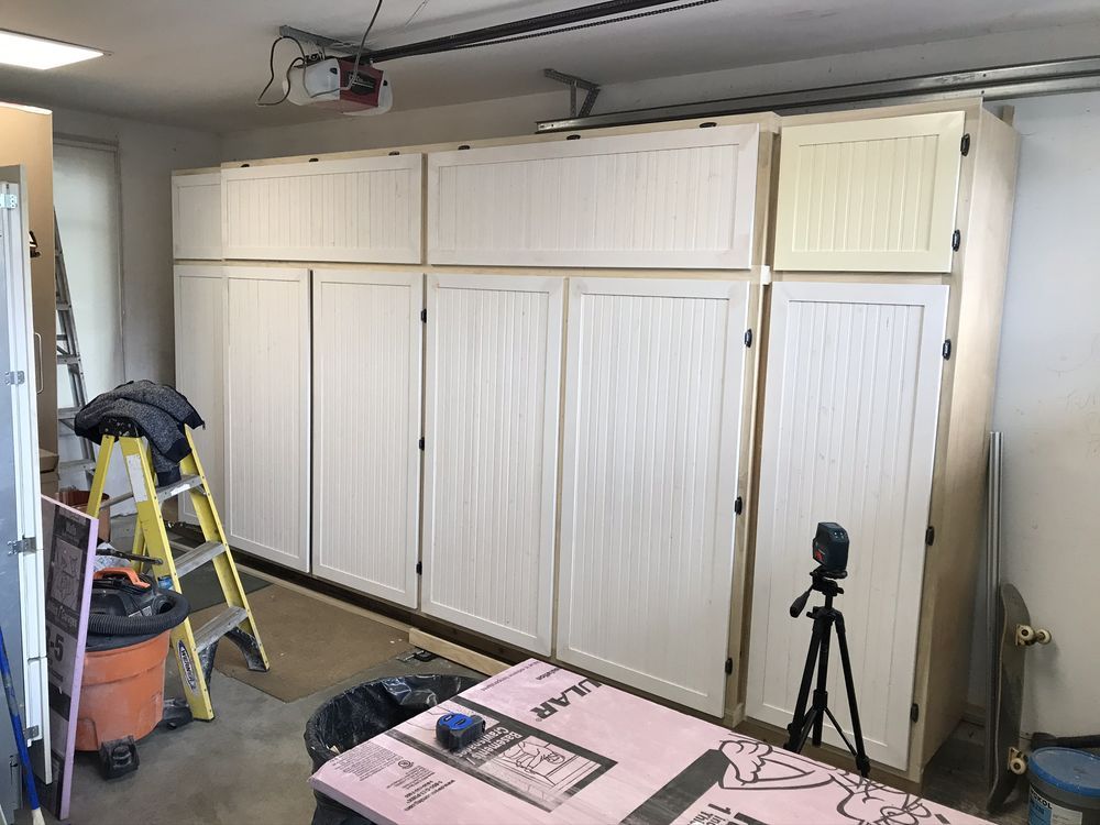 Garage with white storage cabinets, step ladder, and work table.