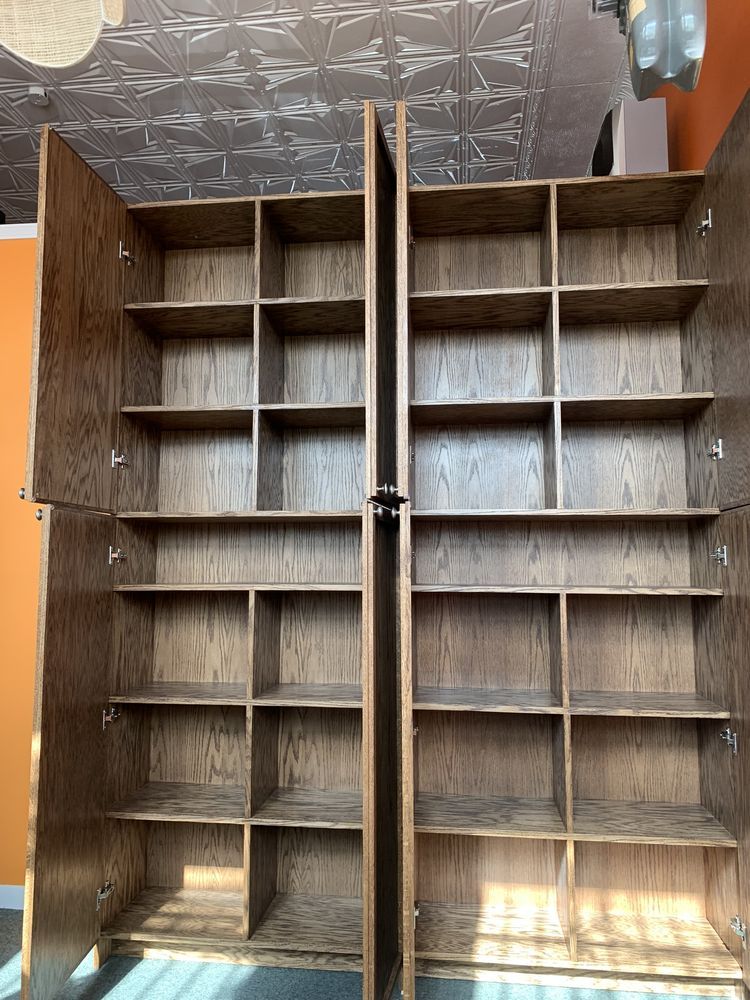 Two tall, wooden cabinets with multiple shelves, doors open.