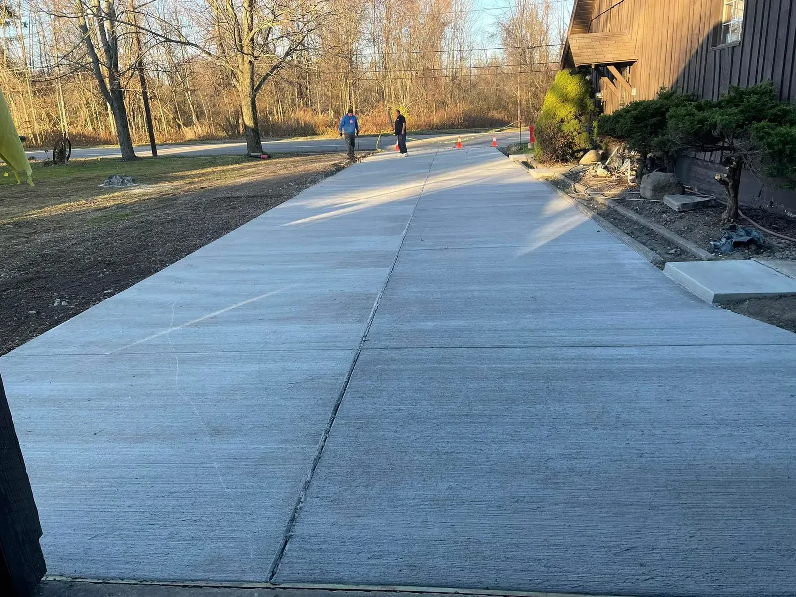 Concrete driveway with two people walking away from the camera on a sunny day.