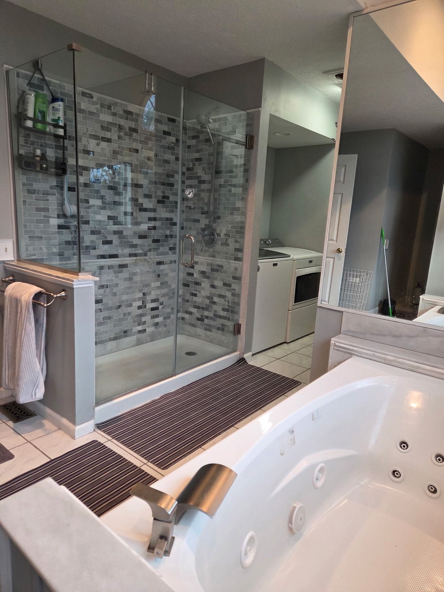 Modern bathroom with glass shower, mosaic tile, and white jacuzzi tub