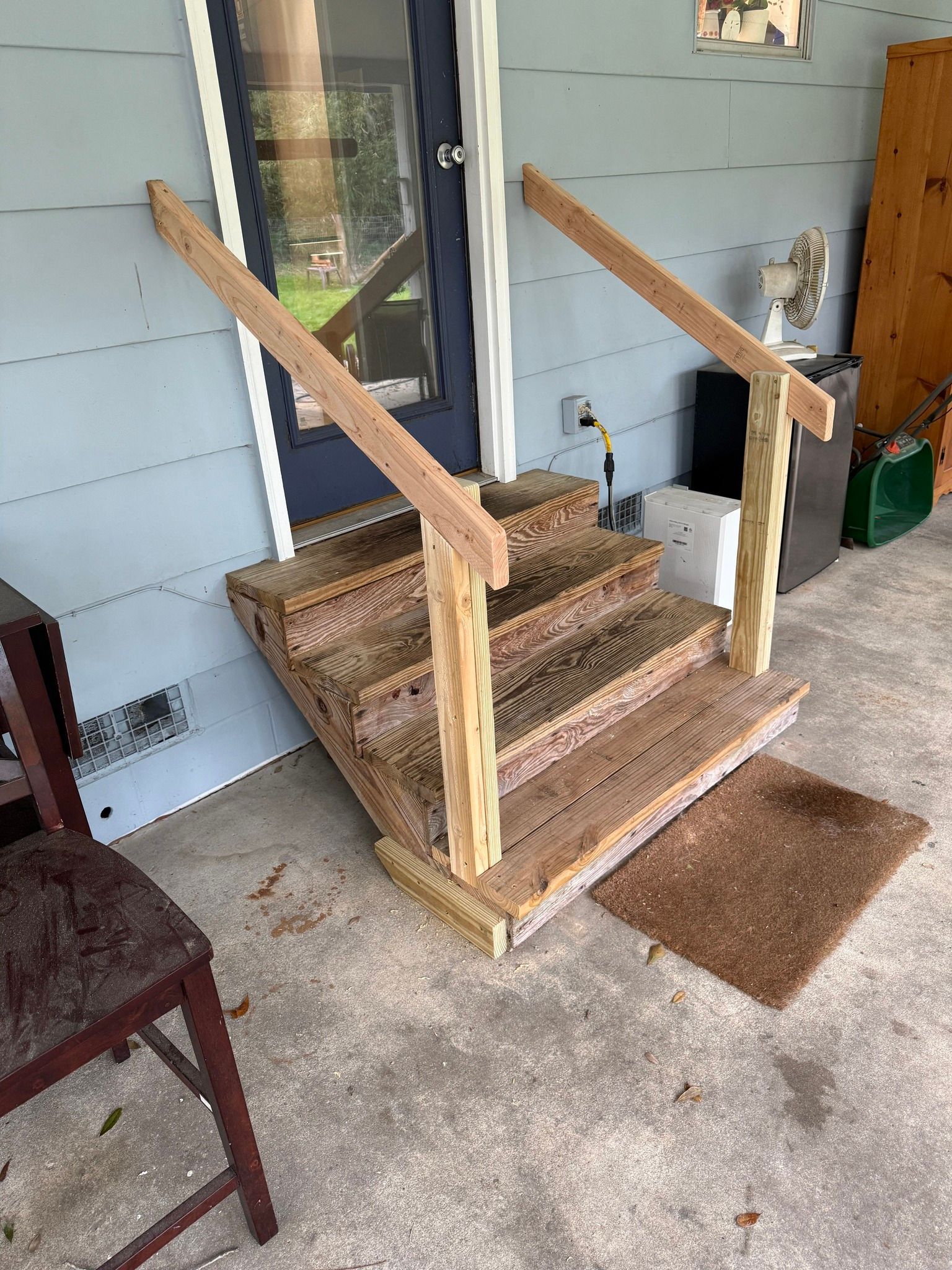 Wooden accessibility ramp with handrails leading to a front porch door.