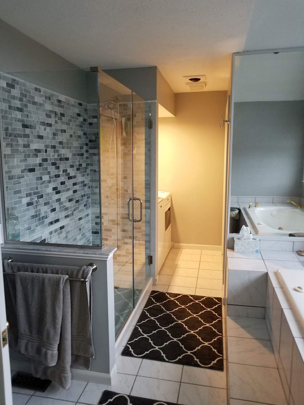 Bathroom with glass shower, tiled floor, vanity sink, and towels hanging on a rack.
