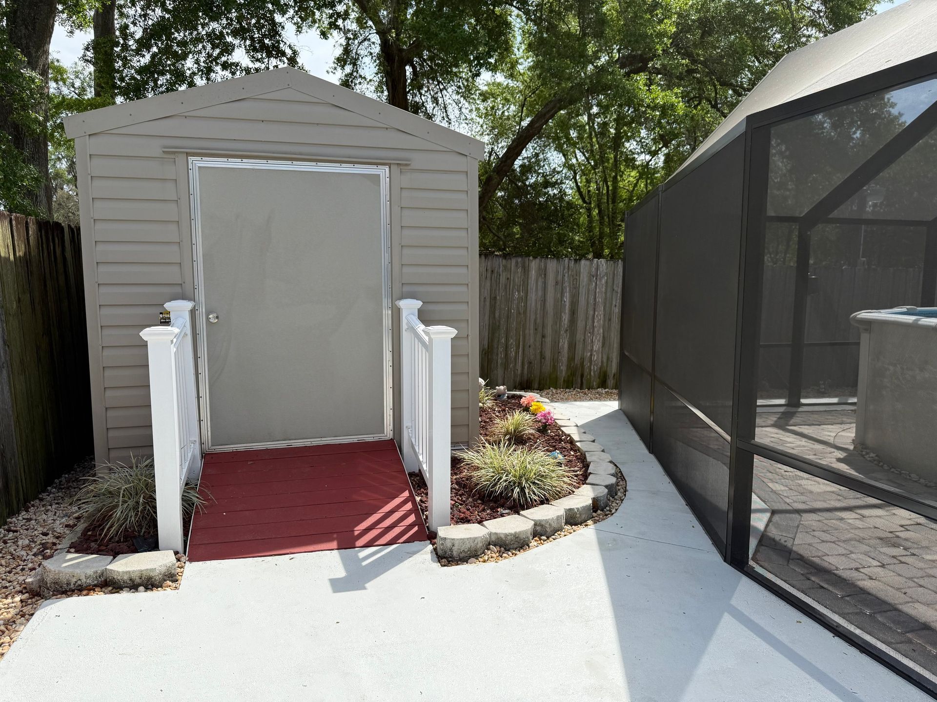 Backyard poolside shed entrance with red ramp, white railings, and screened enclosure beside it
