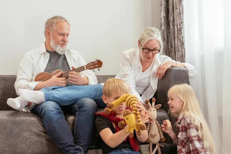 Family sitting on a couch, playing ukuleles and toy instruments in a bright living room