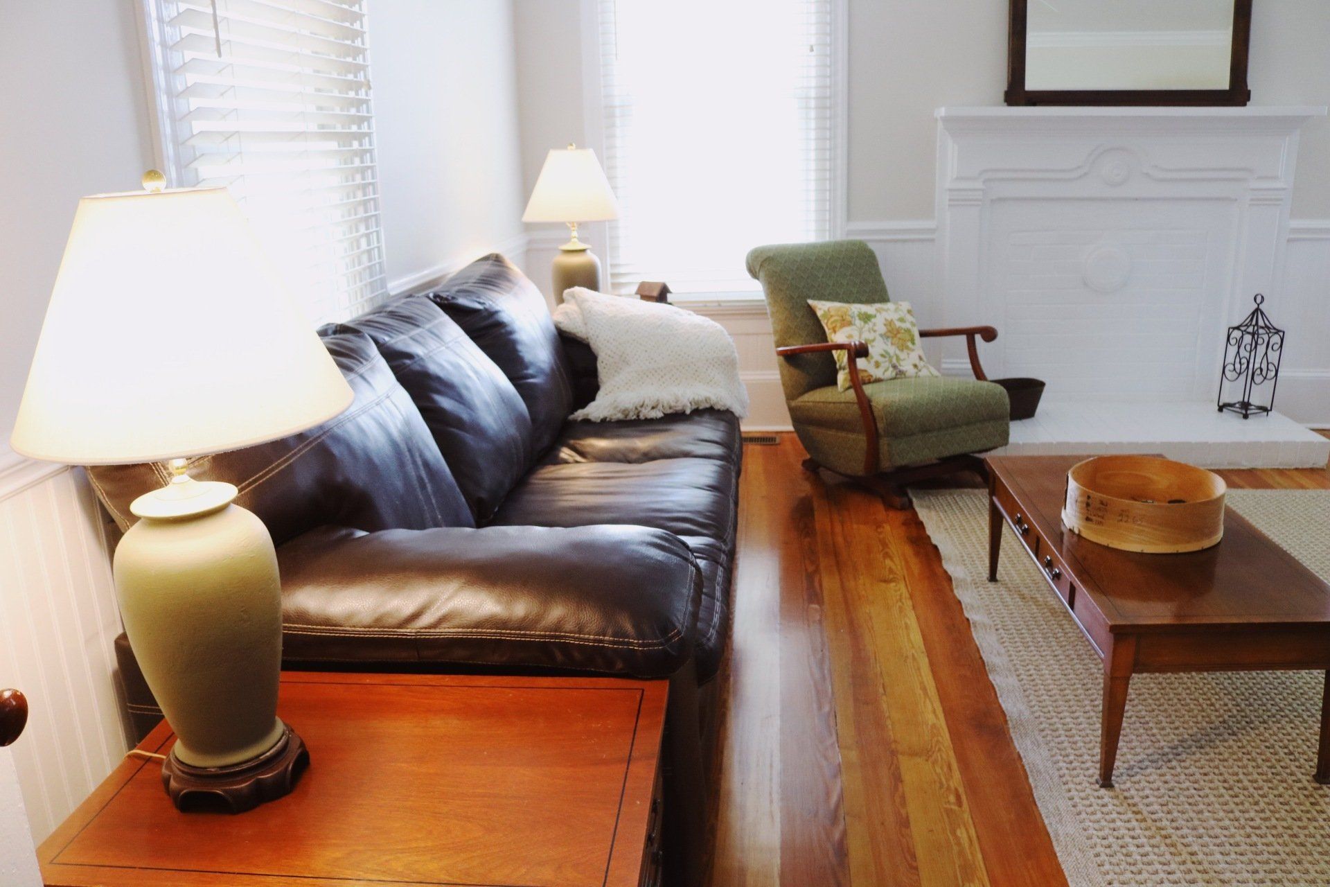 Living room with a dark leather sofa, armchair, fireplace, and lamps.