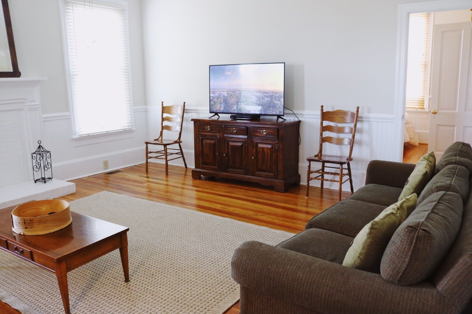 Living room with a sofa, TV on a wooden cabinet, and two chairs.