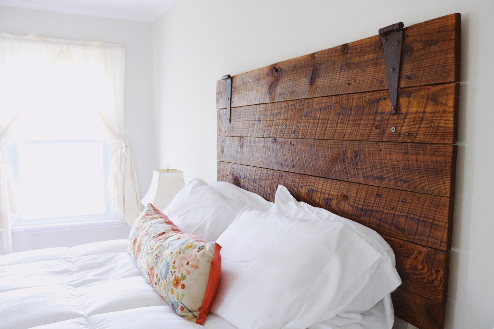 Bedroom with a wooden headboard, white bedding, and a decorative pillow.