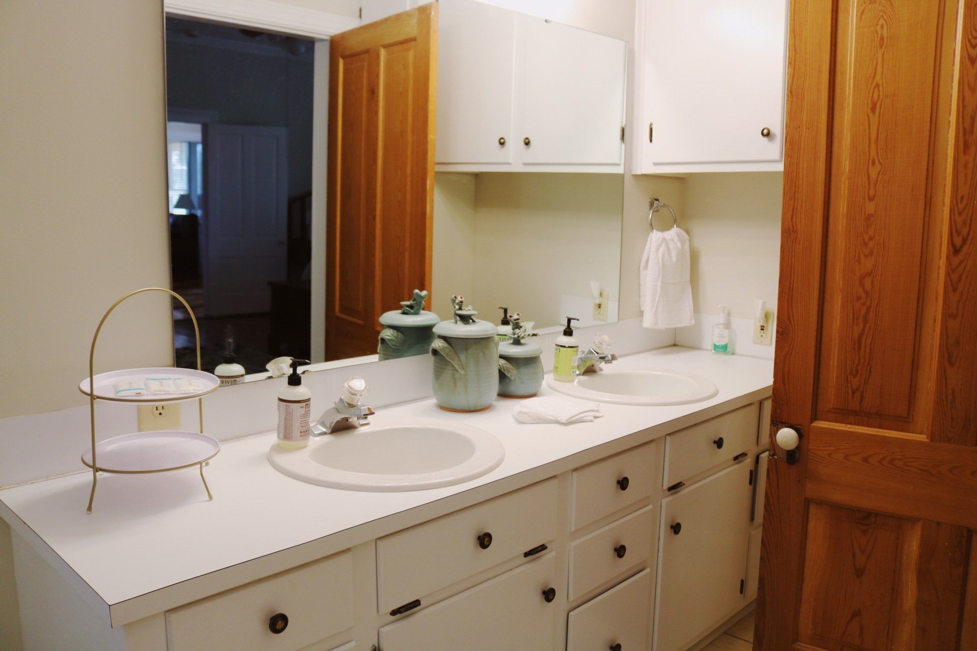 Bathroom with white vanity, two sinks, and wooden door.