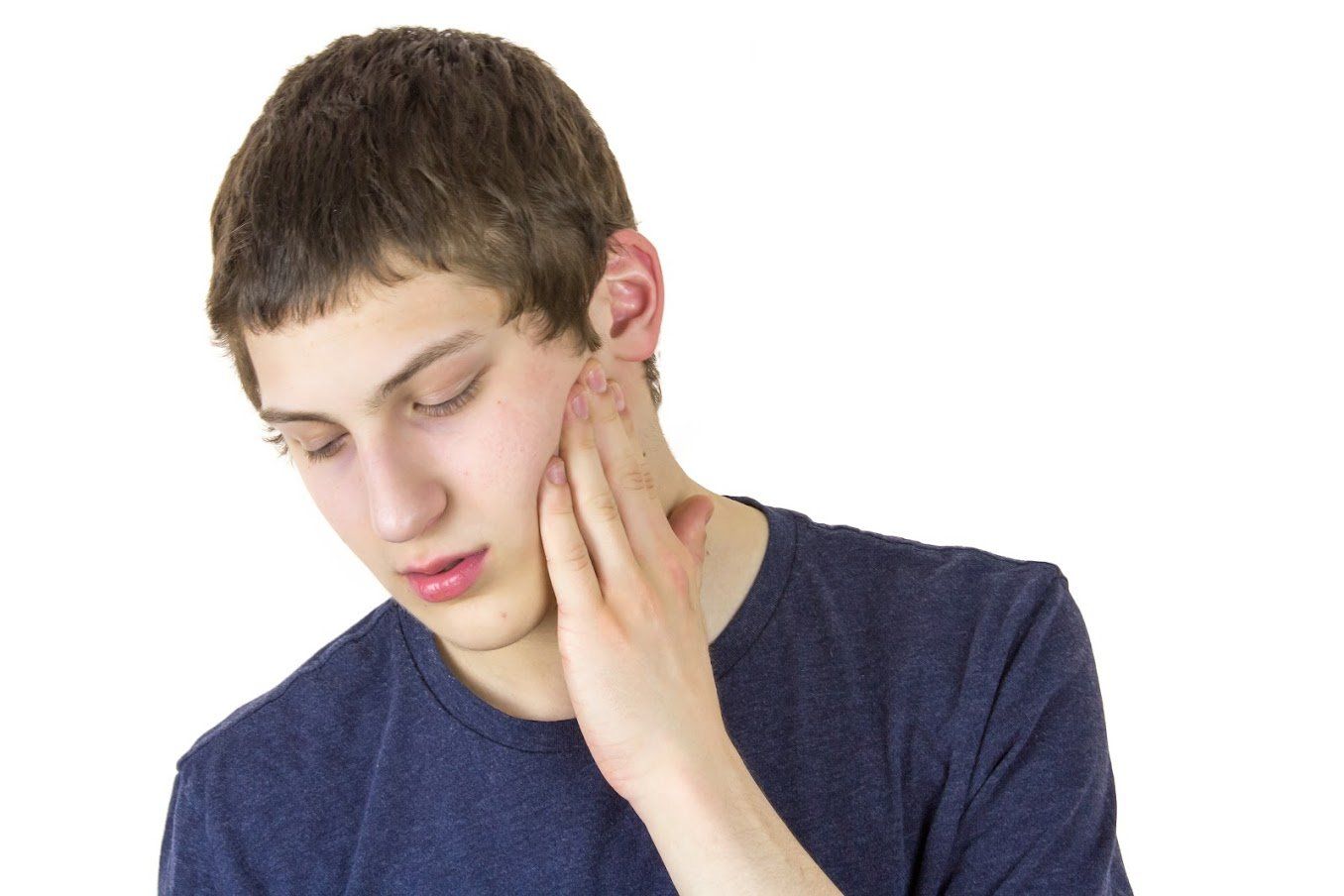 Teenager with hand on jaw, showing discomfort.