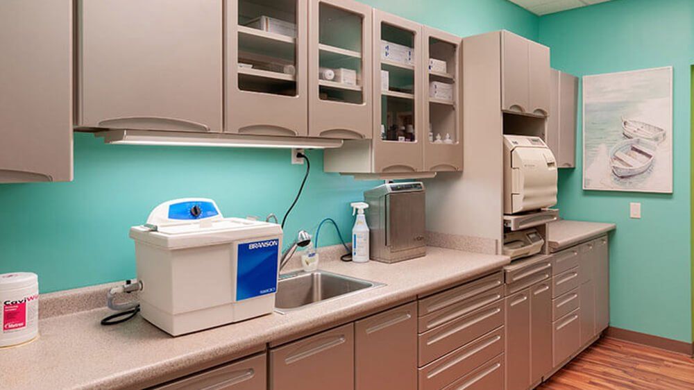 Dental office sterilizing station with blue walls, cabinets, and equipment.