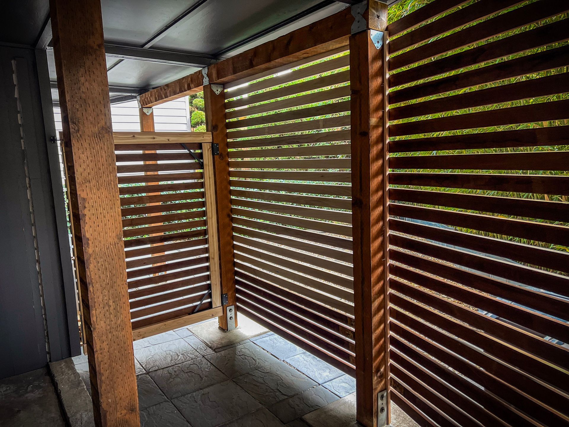 Black chain-link fence with a black top rail, viewed from a close, angled perspective, outdoors.