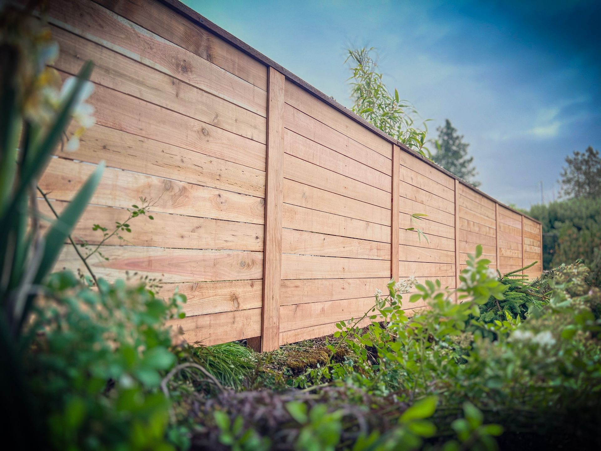 Black chain-link fence with a black top rail, viewed from a close, angled perspective, outdoors.