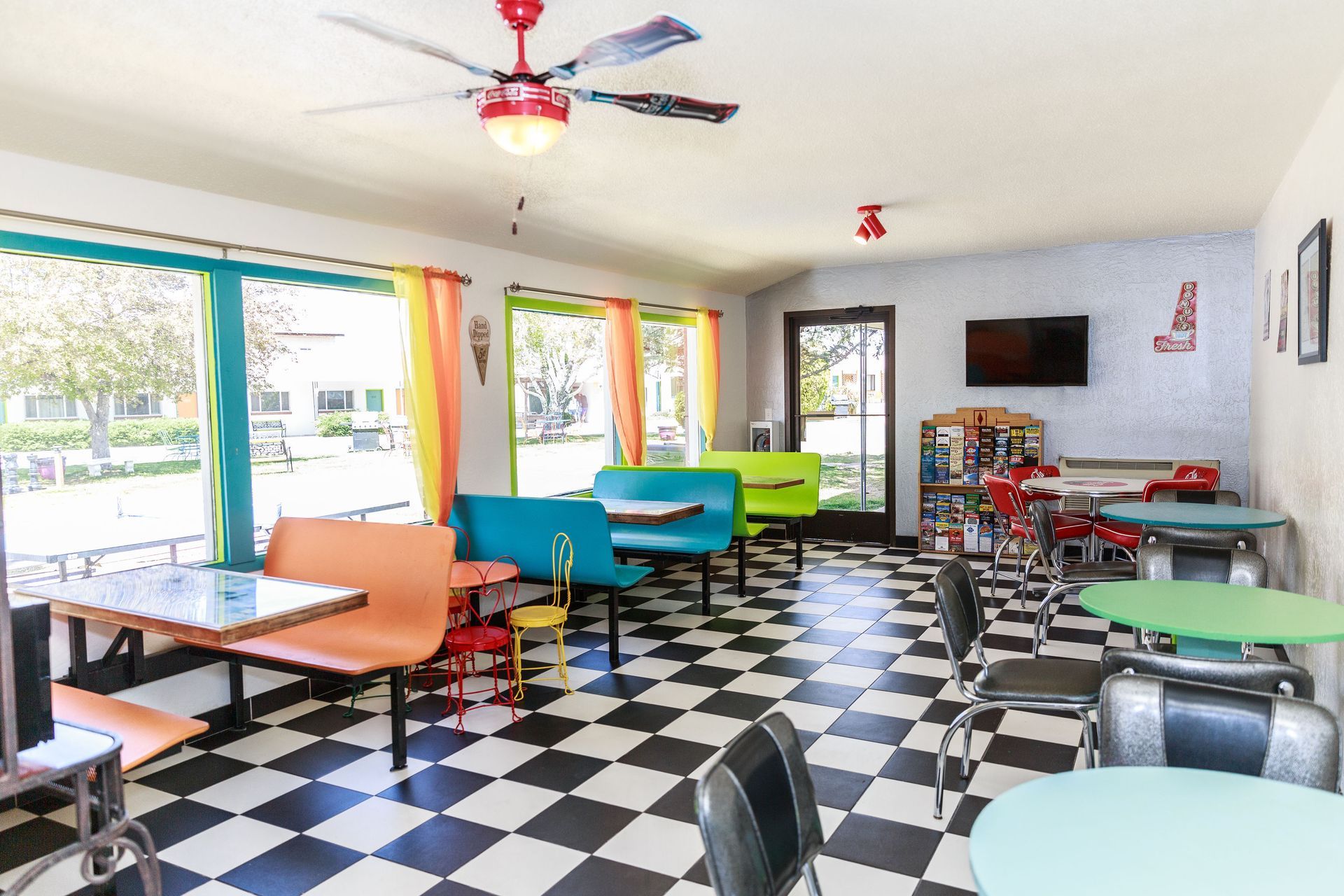 Retro diner interior: booths, tables, checkered floor, colorful accents, windows overlooking the courtyard and parking lot