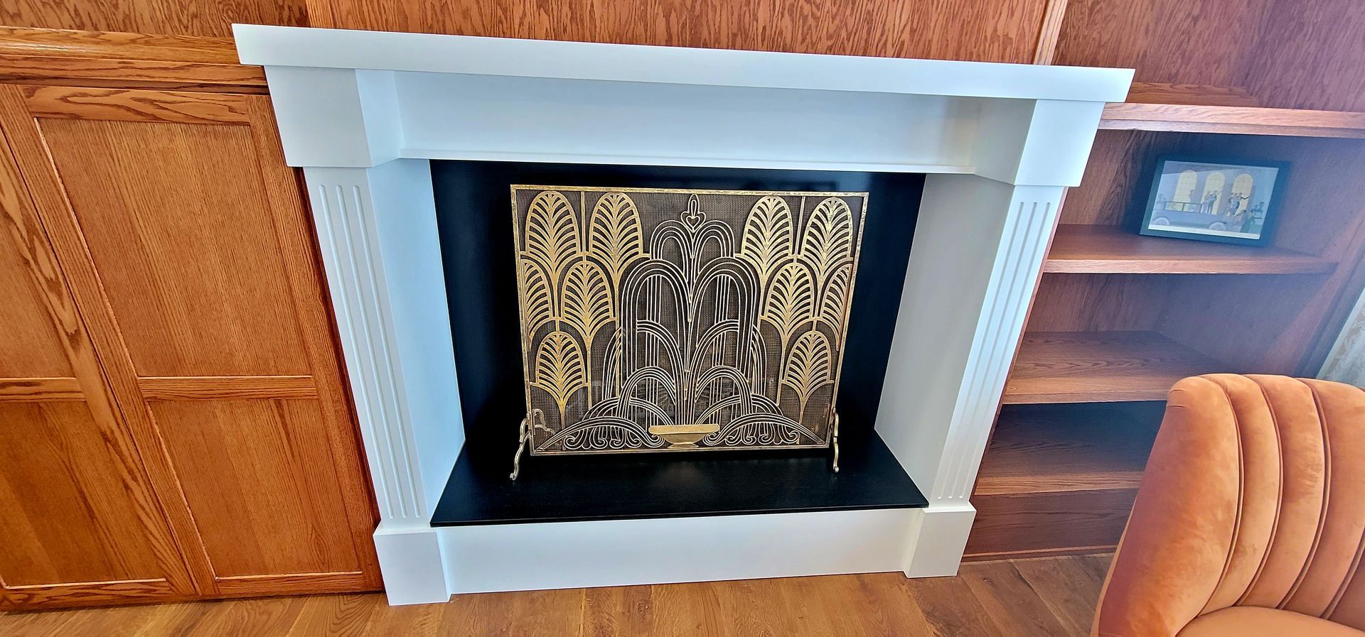 White fireplace with a decorative brass screen  in the Great Gatsby  Suite.