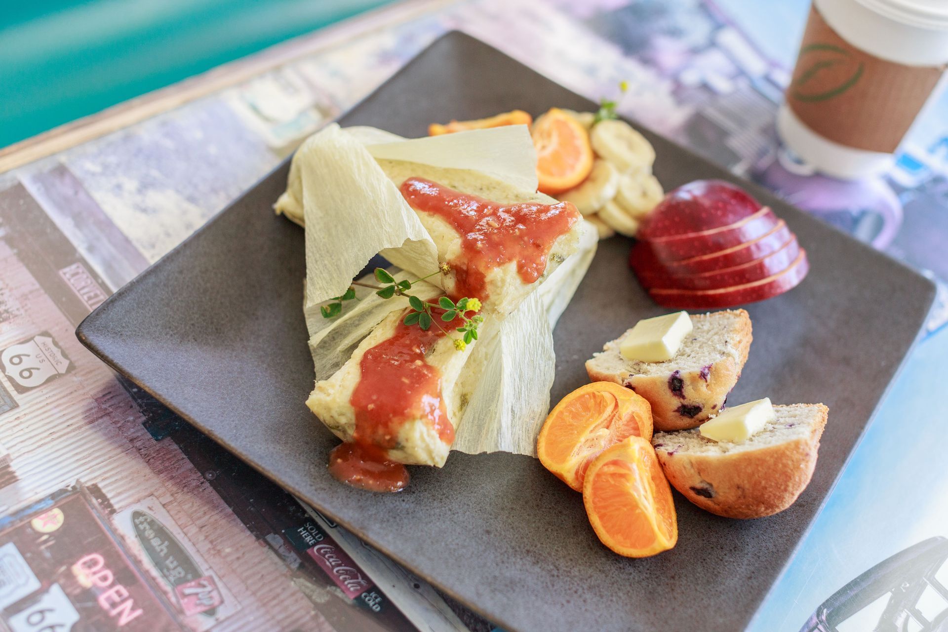 Plate with tamale, fruit, and bread, served with coffee.