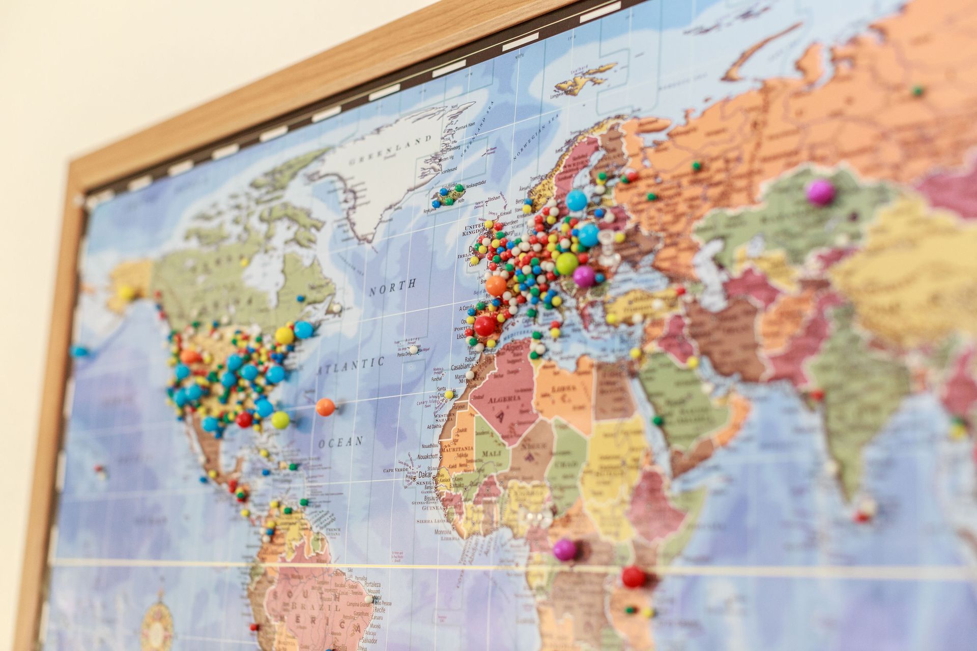 World map with colorful push pins marking travelers home locations..