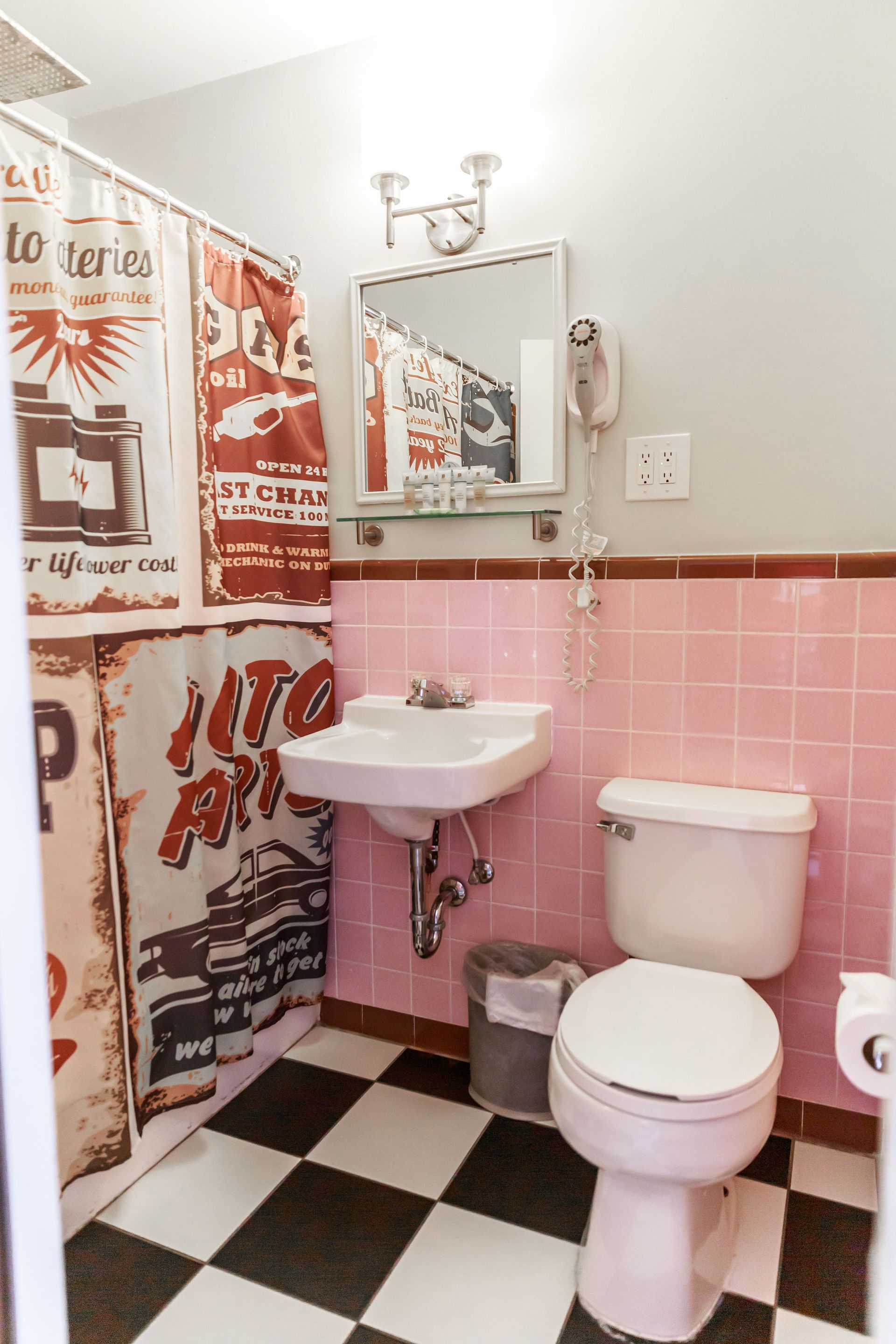 Bathroom with pink tile walls, black and white checkered floor, shower curtain, and toilet.