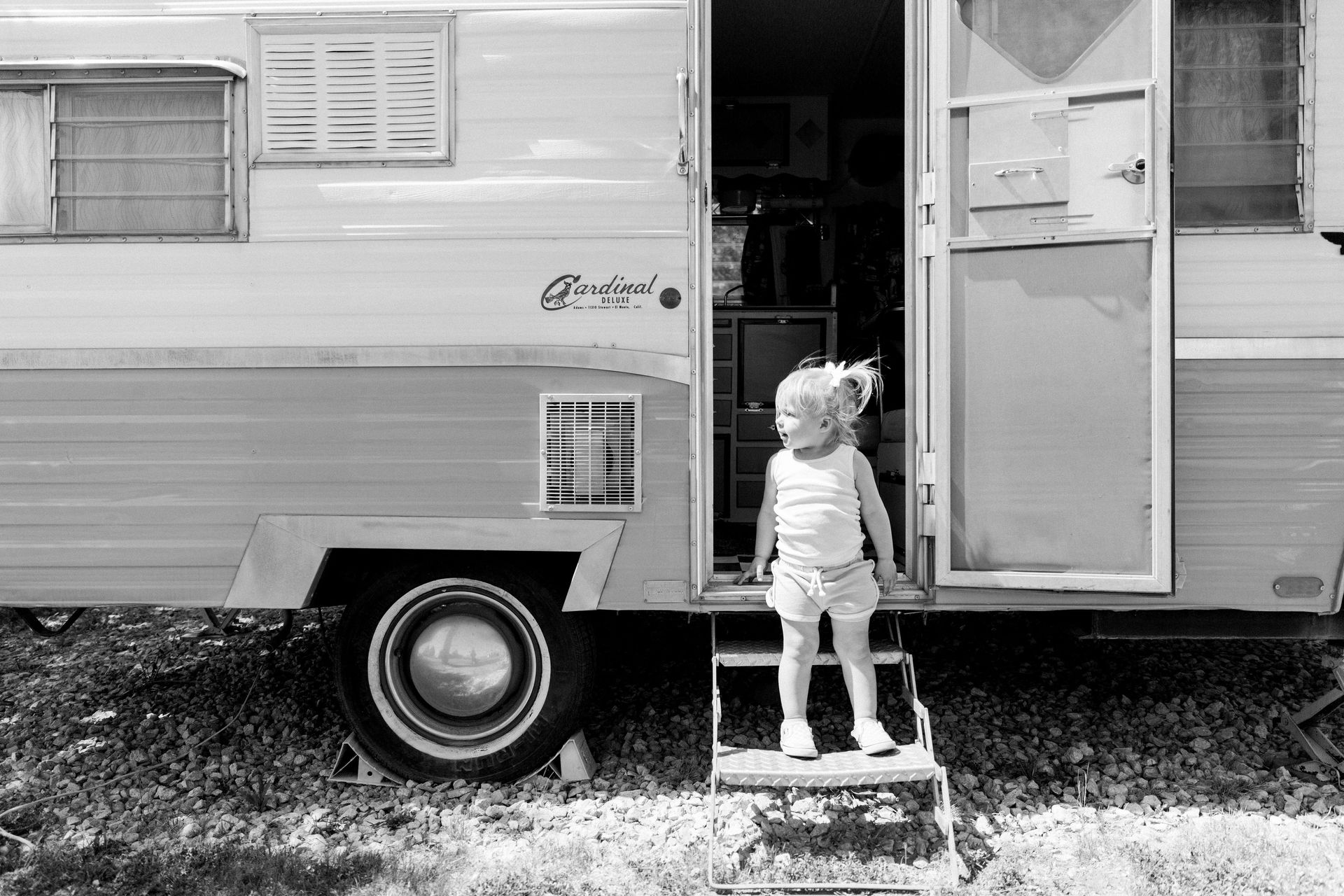 Child standing in doorway of vintage travel trailer at The Retro Inn. The photo is in black and white.