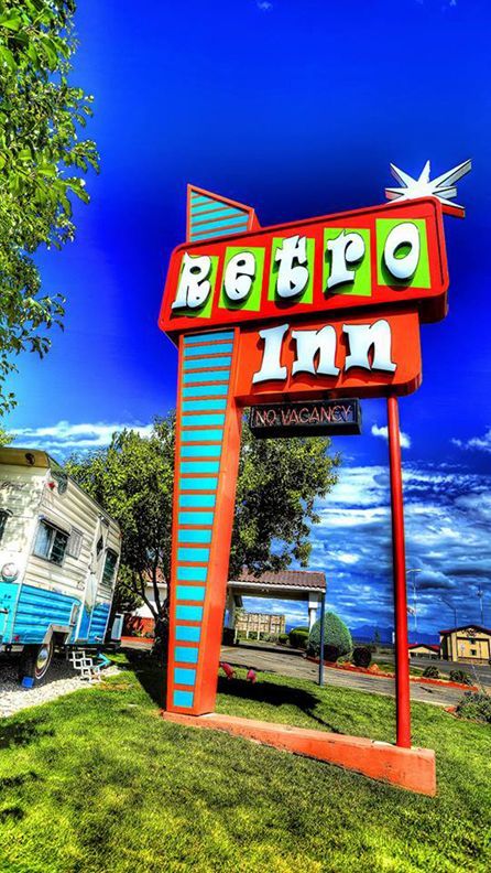 Retro Inn sign with a teal and orange color scheme, against a bright blue sky. A vintage trailer is visible.