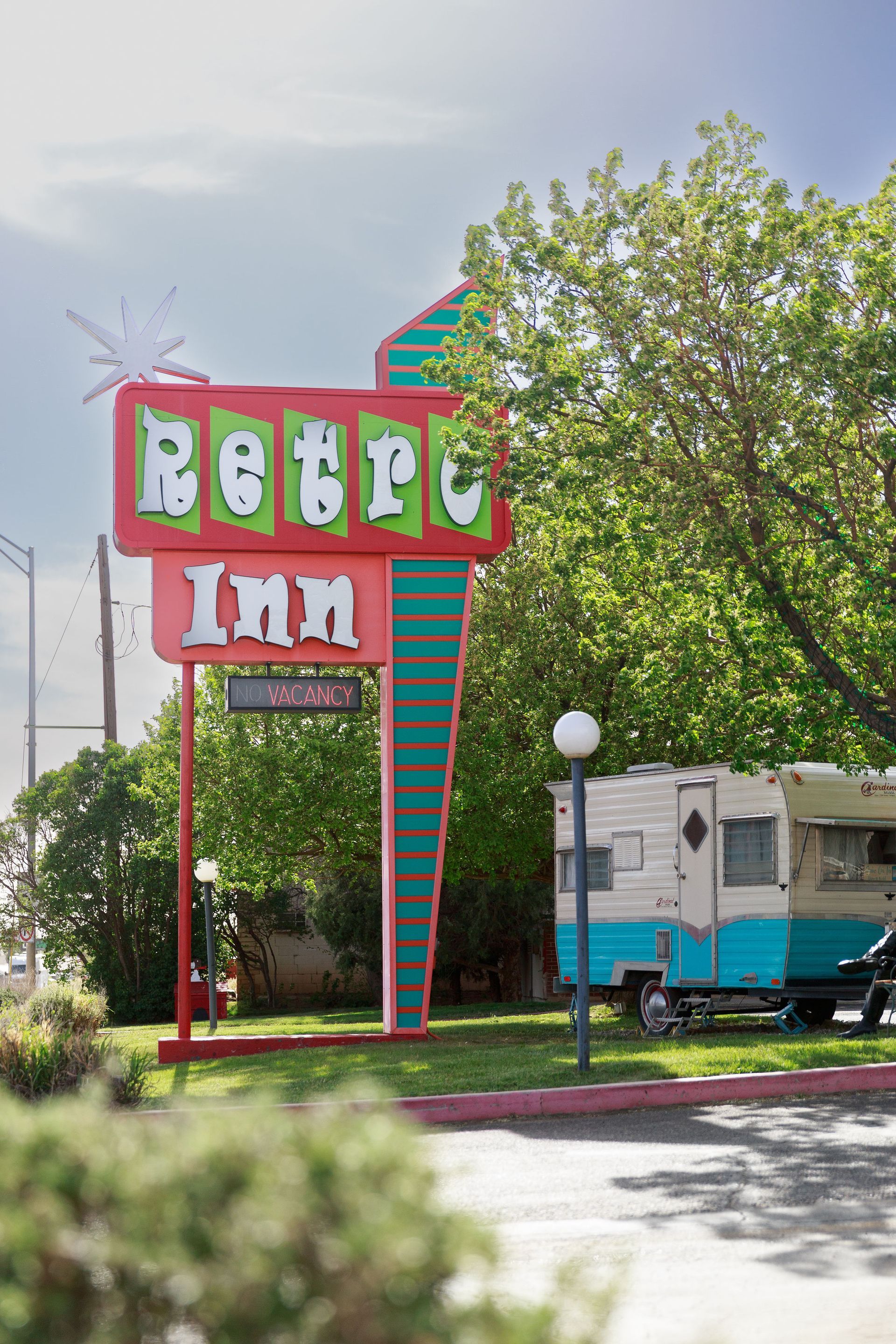 Retro Inn motel sign with turquoise, red, and white lettering, vintage trailer in the background.