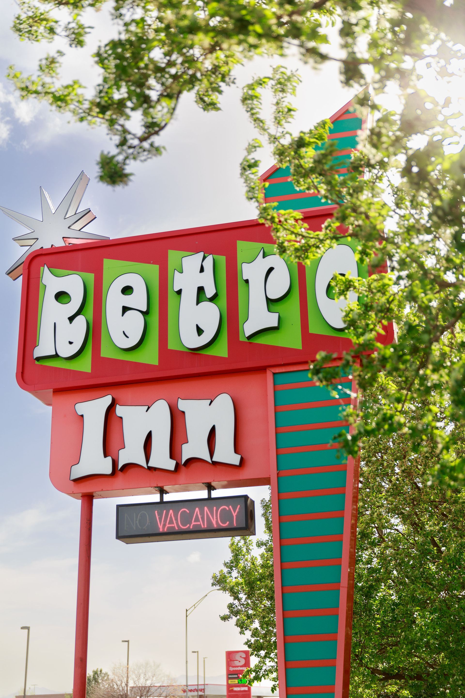 Retro Inn motel sign with turquoise, red, and white lettering, vintage trailer in the background.