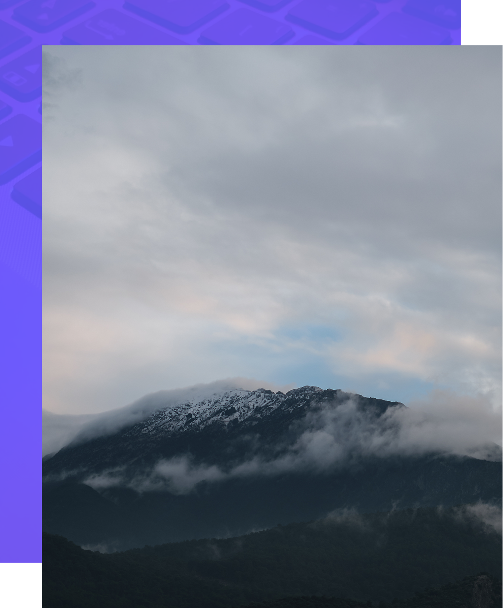 Snow-dusted mountain peak beneath gray clouds with a hint of sunset color