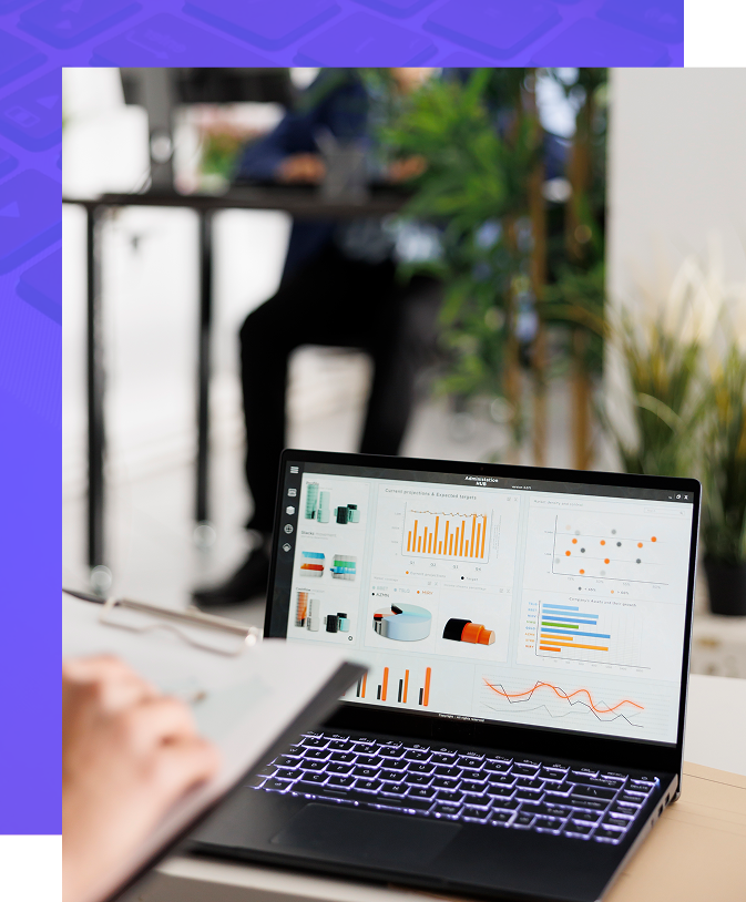 Laptop displaying charts and graphs, person working at desk, office setting.