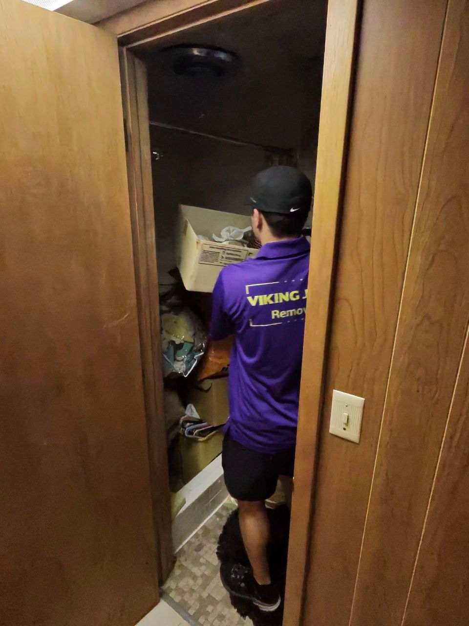 A man in a purple shirt is standing in a doorway.