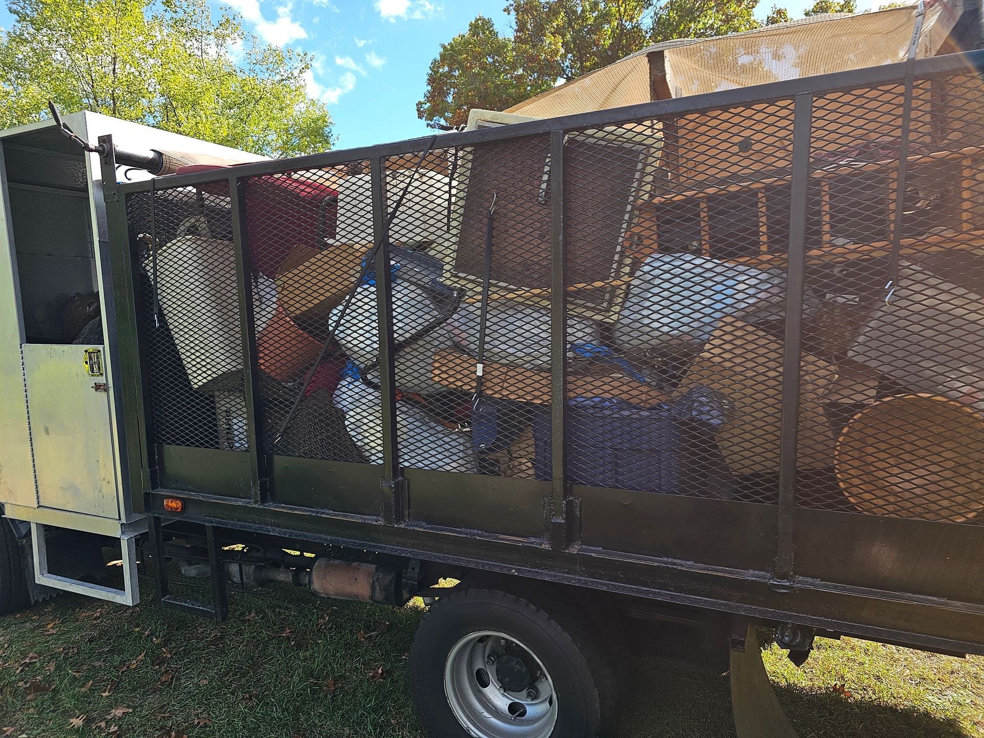 A dump truck filled with lots of trash is parked in the grass.