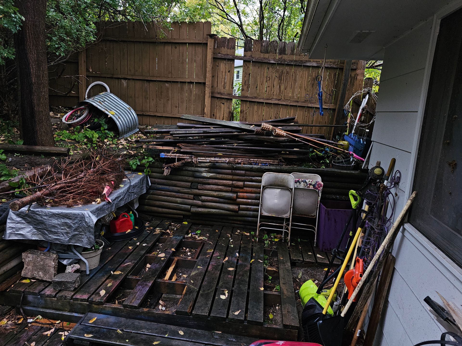 A wooden deck with chairs and a fence in the background