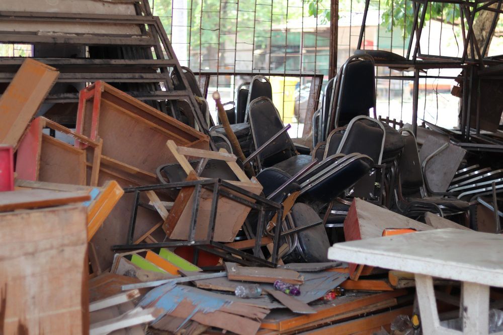A bunch of old appliances are sitting on the ground next to a green recycling bin.