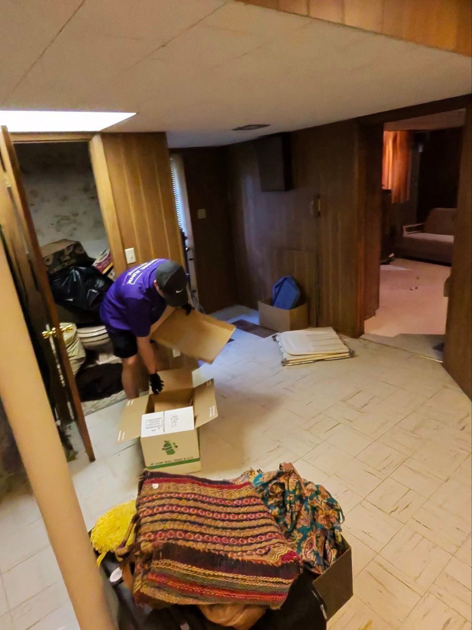 A man in a purple shirt is opening a cardboard box