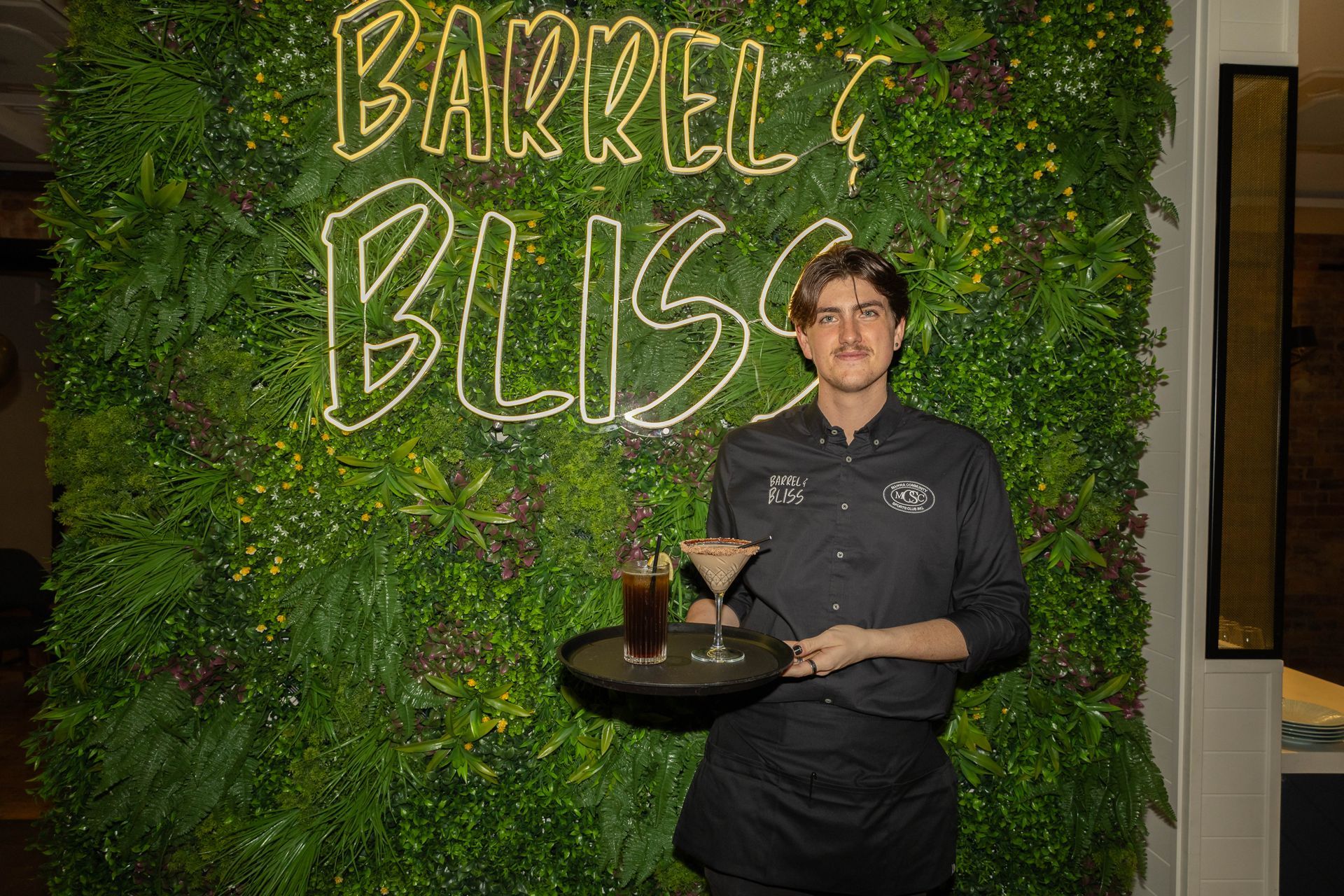 Bartender holds tray with drinks in front of 