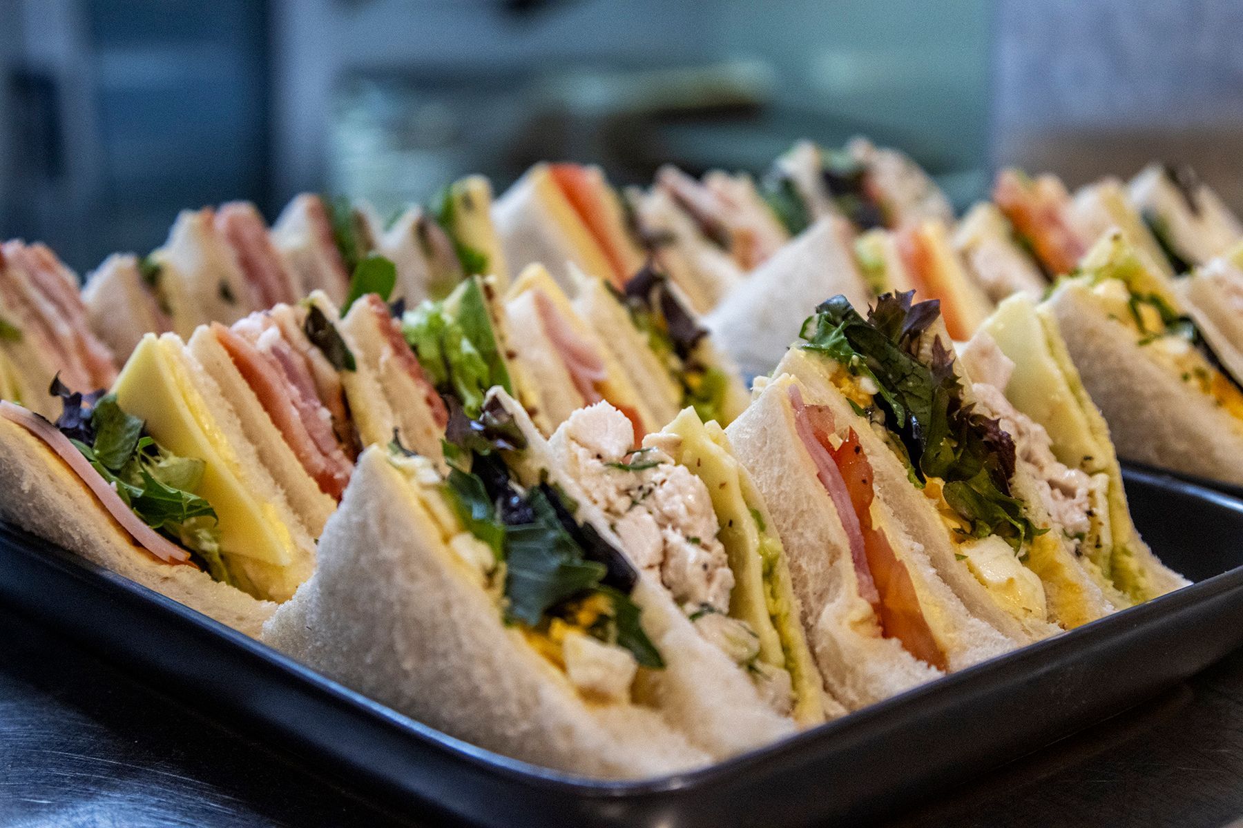 Tray of assorted sandwiches with various fillings, cut in triangles.