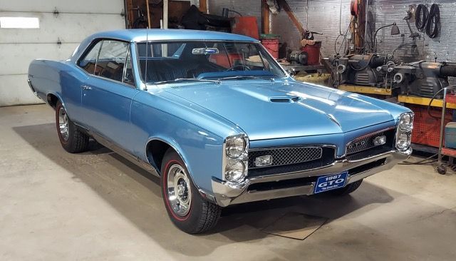 Blue classic Pontiac GTO coupe parked in a garage with its hood closed