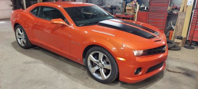 Orange sports coupe in a garage, shown from the front-left side.