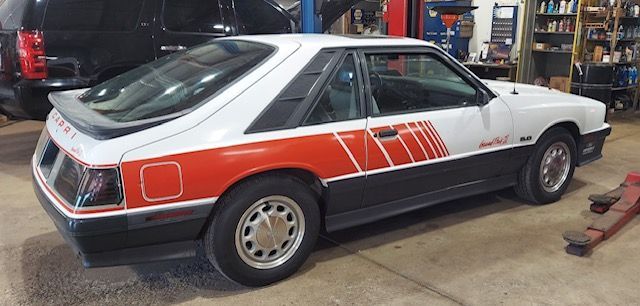 Classic white and red race car in a workshop, side view on a lift with tools nearby